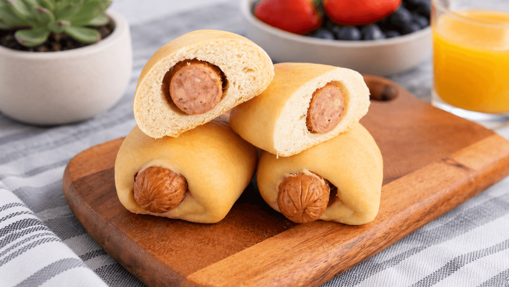 Sausage kolaches sliced open on a wooden board